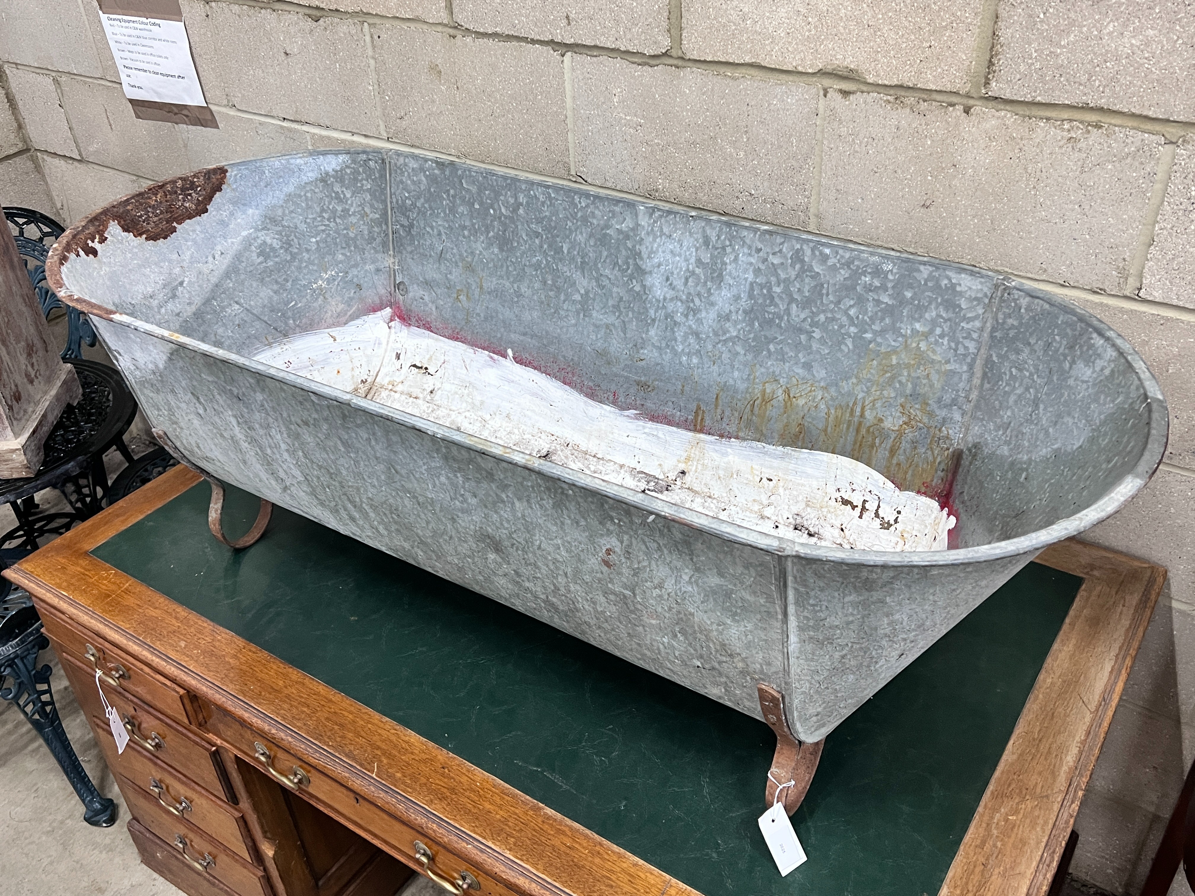 A vintage galvanised trough on wrought iron feet, length 146cm, depth 62cm, height 49cm